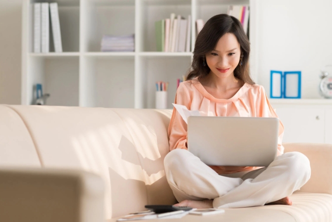 a woman sitting on a couch working on a laptop