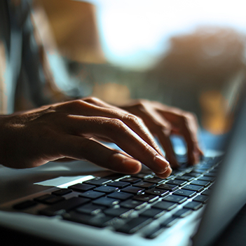 Fingers typing on a laptop keyboard.