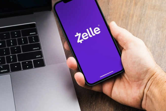 a person holding their mobile phone with Zelle on the screen