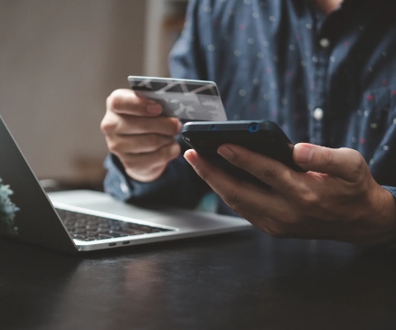 a person with a credit/debit card in one hand and a mobile phone in the other hand